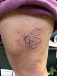 a tattoo of a bee on a woman's thigh