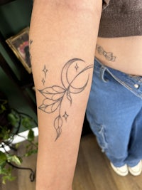 a woman's arm with a tattoo of a crescent moon and stars