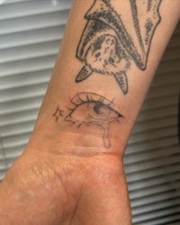 a woman's wrist with a tattoo of an eye and a bat