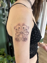 a woman with a tattoo of two teddy bears on her arm