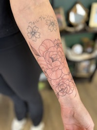 a woman with a pink flower tattoo on her forearm